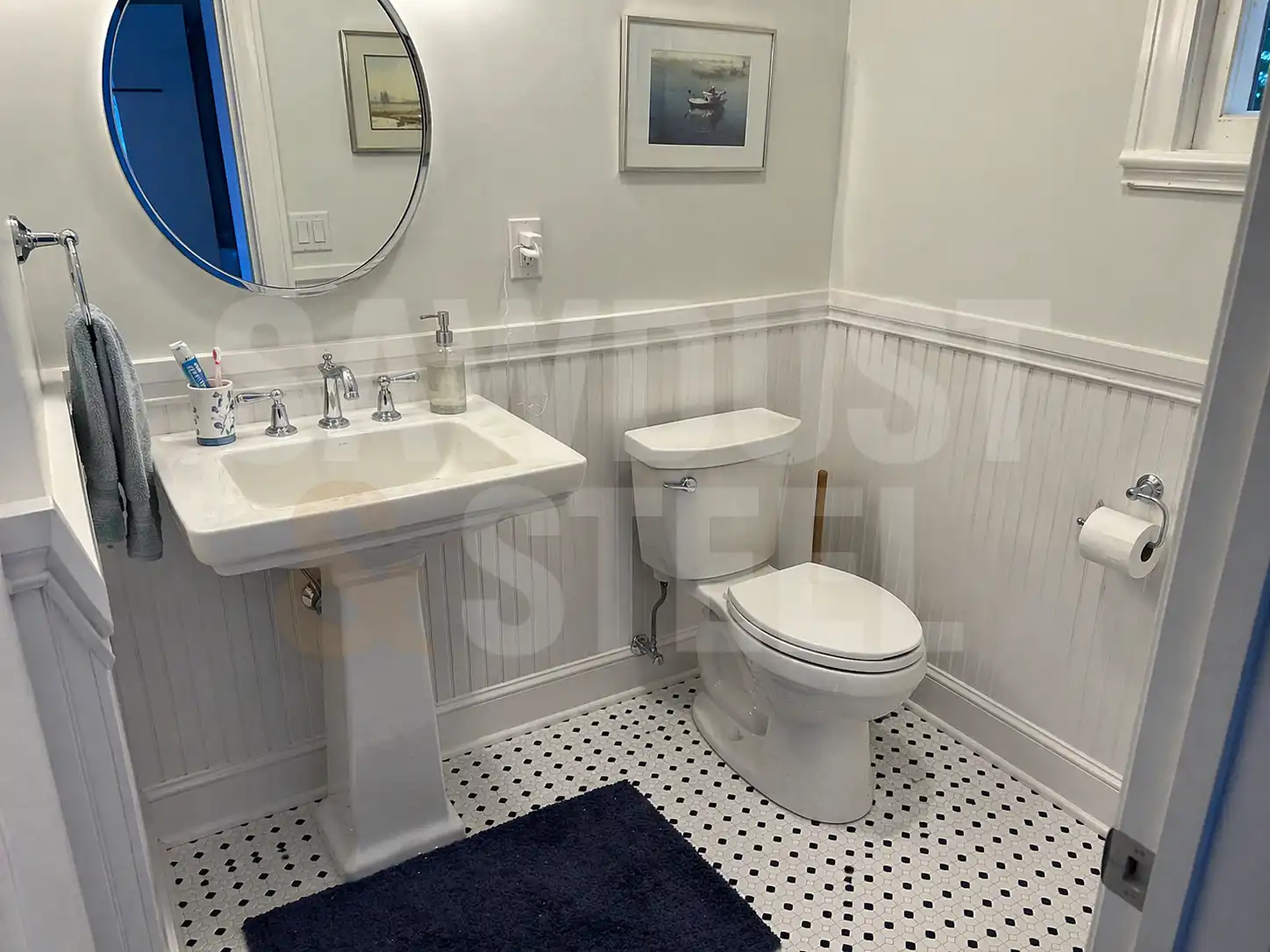 Powder room with pedestal sink, beadboard wainscoting, and mosaic floor