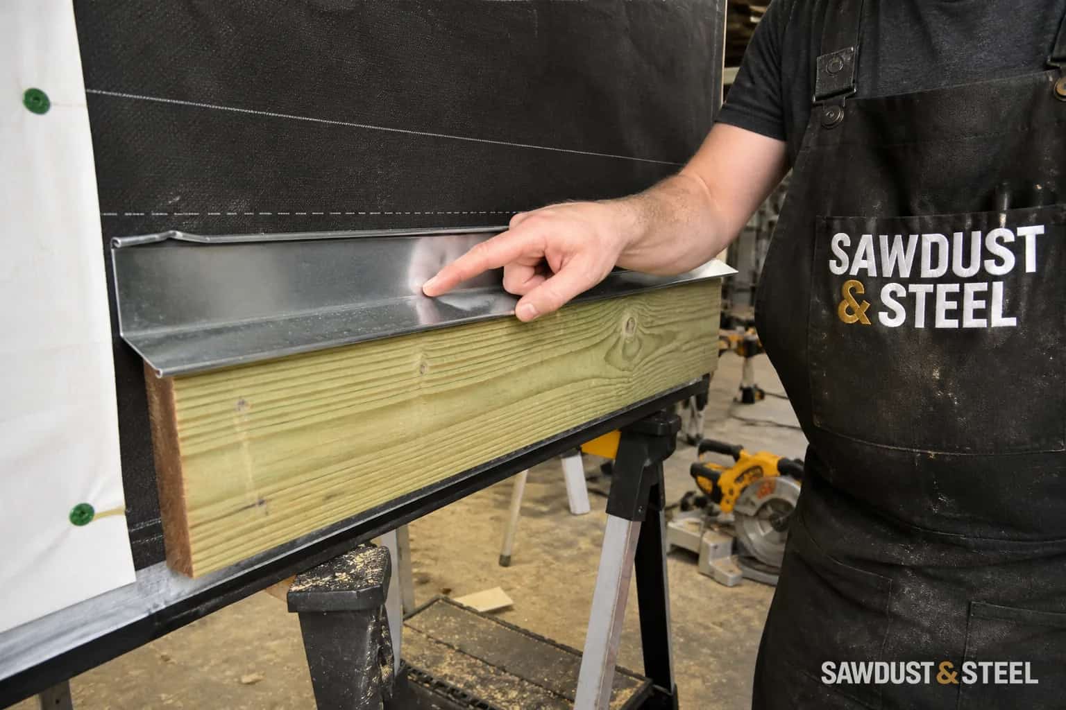 Carpenter pointing to cap flashing on a deck ledger mock-up