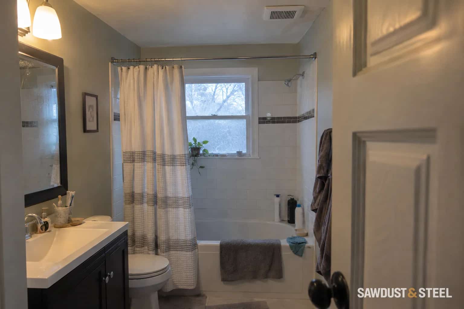 A small bathroom with a ceiling extractor, a faint nearby stain, and towels beside the bath