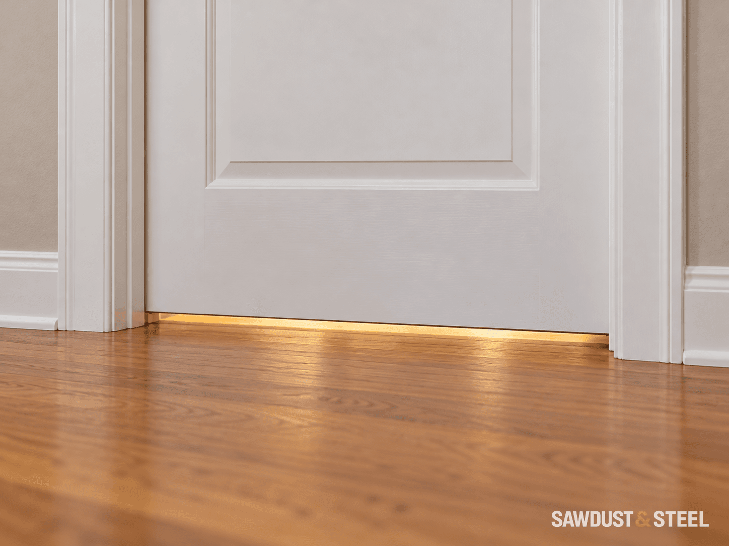Warm light showing through the gap beneath a closed white interior door