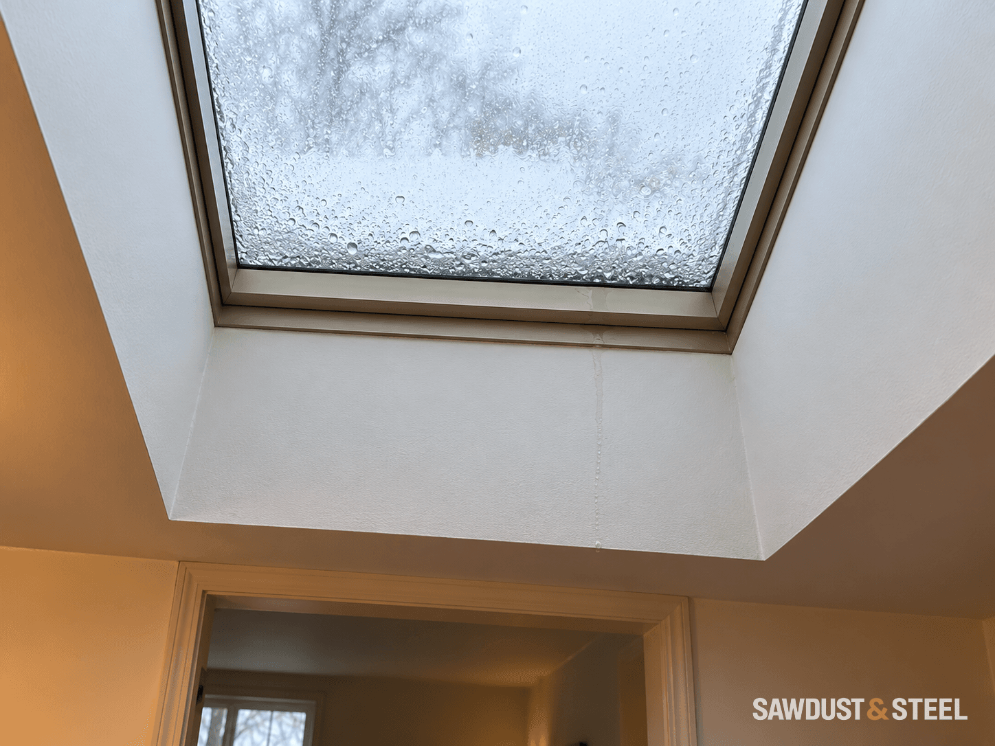 Droplets on skylight glass and a narrow wet trail below the lower frame