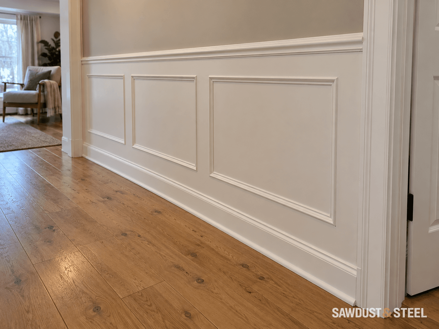 White rectangular wall mouldings, chair rail and baseboard beside oak hallway flooring