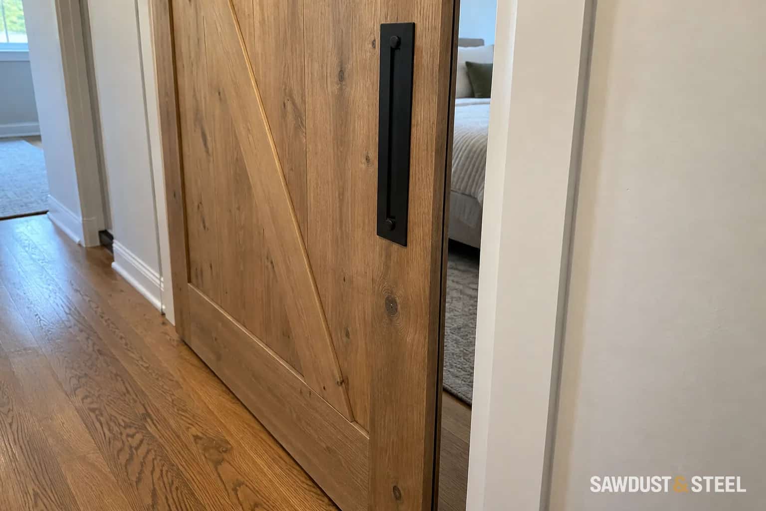 Wood sliding barn door with a black handle and an open gap beside the doorway
