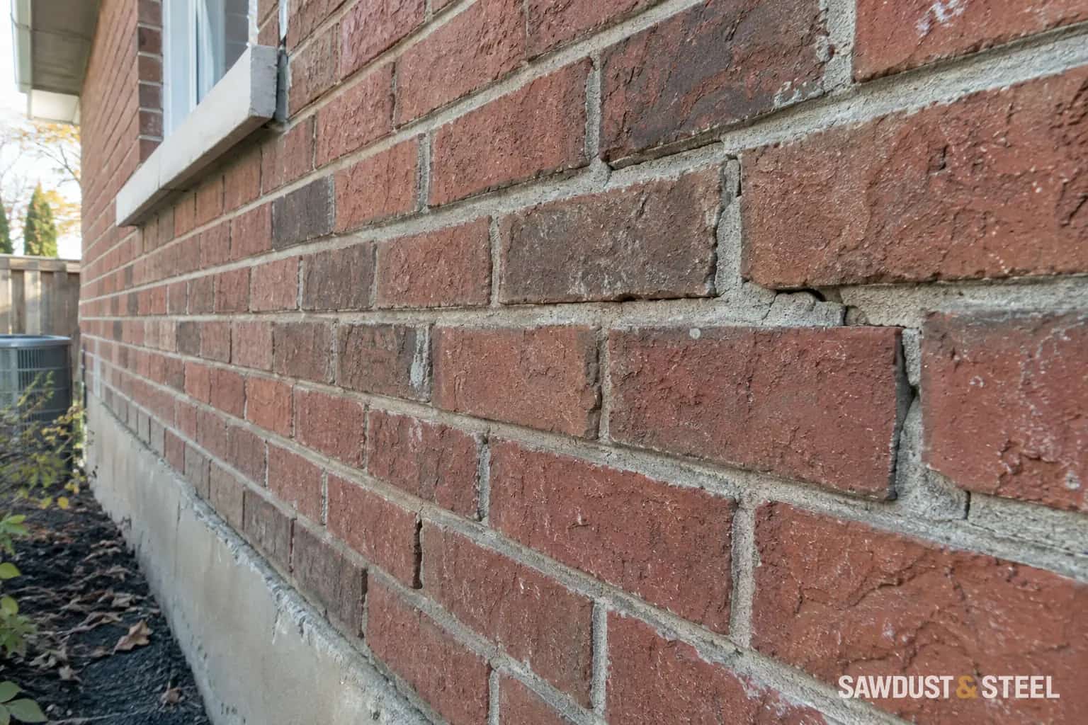 Weathered red brickwork with localized cracks and recesses in the mortar joints