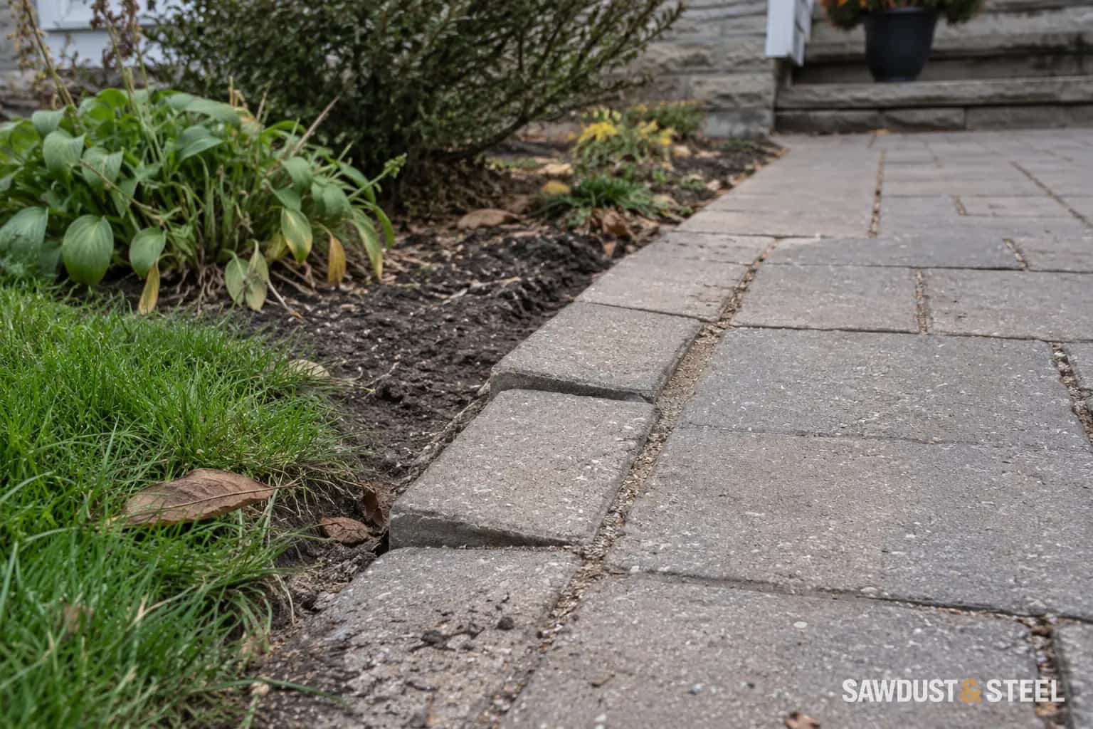 Uneven border pavers beside a planted bed and a paved garden path