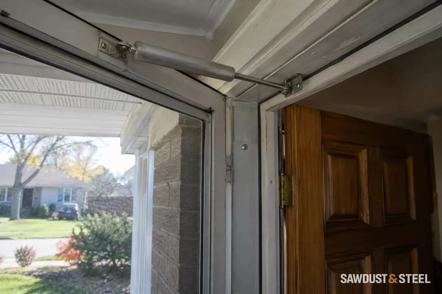 Pneumatic closer cylinder and rod between an aluminum storm door and its frame