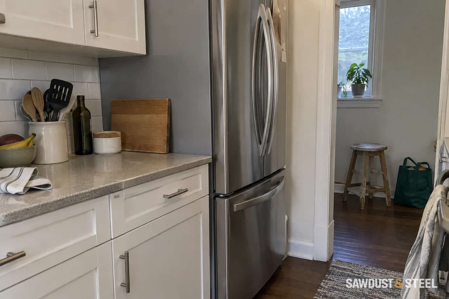 A stainless French-door refrigerator with doors and handles projecting beyond neighbouring cabinet fronts