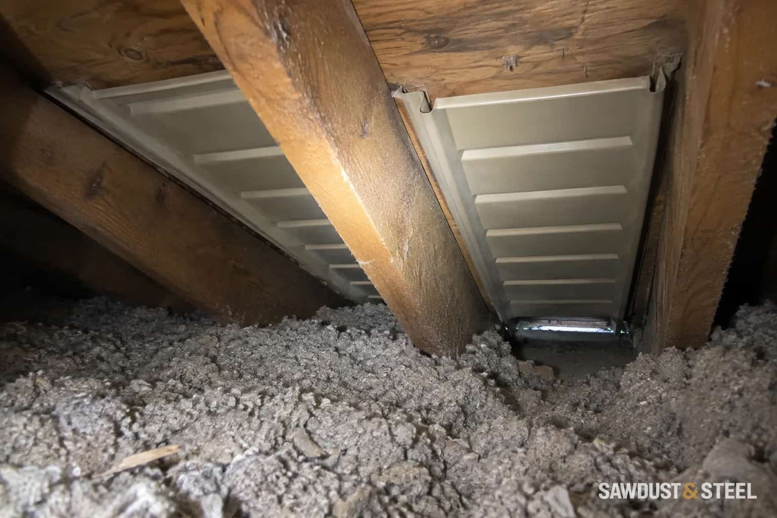 Attic ventilation baffles between timber rafters above loose cellulose insulation at the eaves