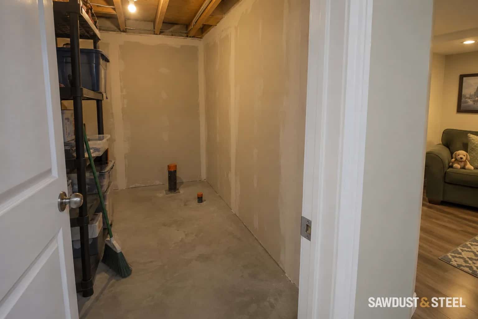 Unfinished drywall and an open ceiling in a basement renovation.