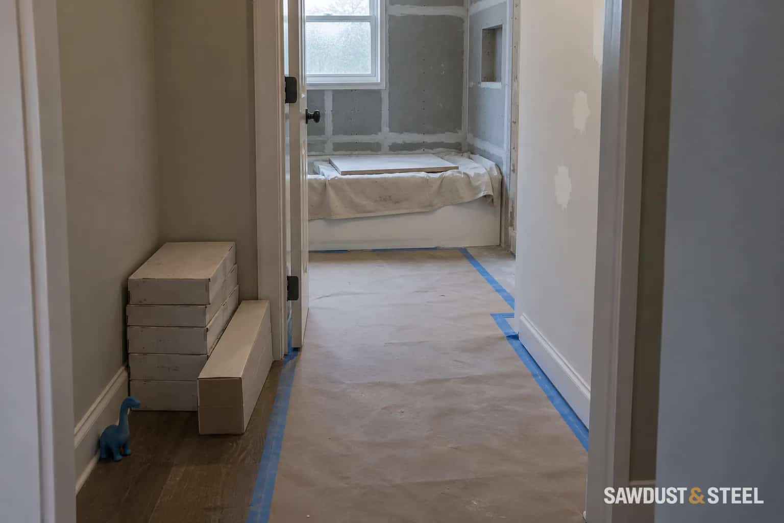 Protected hallway floor leading to a bathroom with a covered bathtub