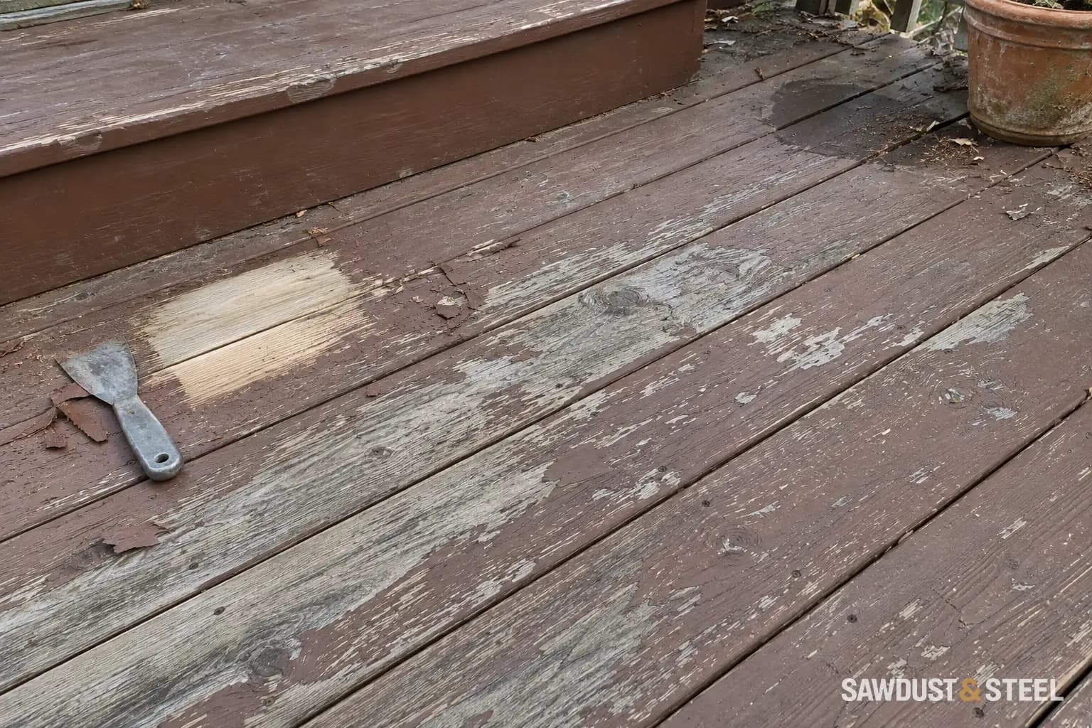 Peeling brown deck stain and a small stripped test patch beside a worn step and planter
