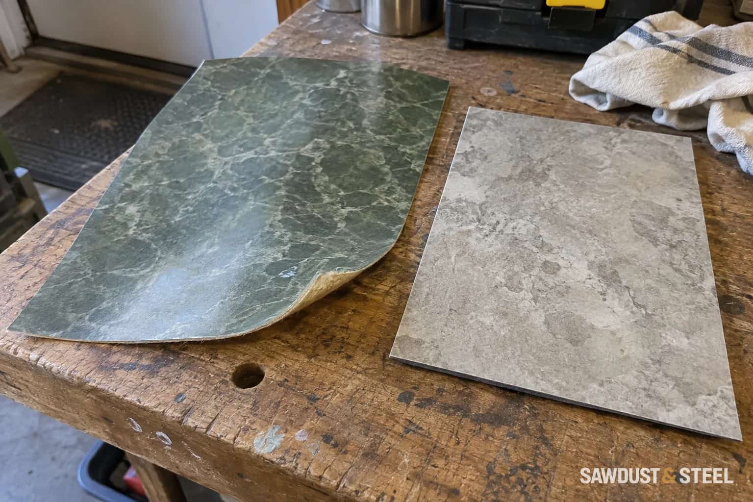 Two resilient flooring offcuts with different surfaces and backings on a workbench.