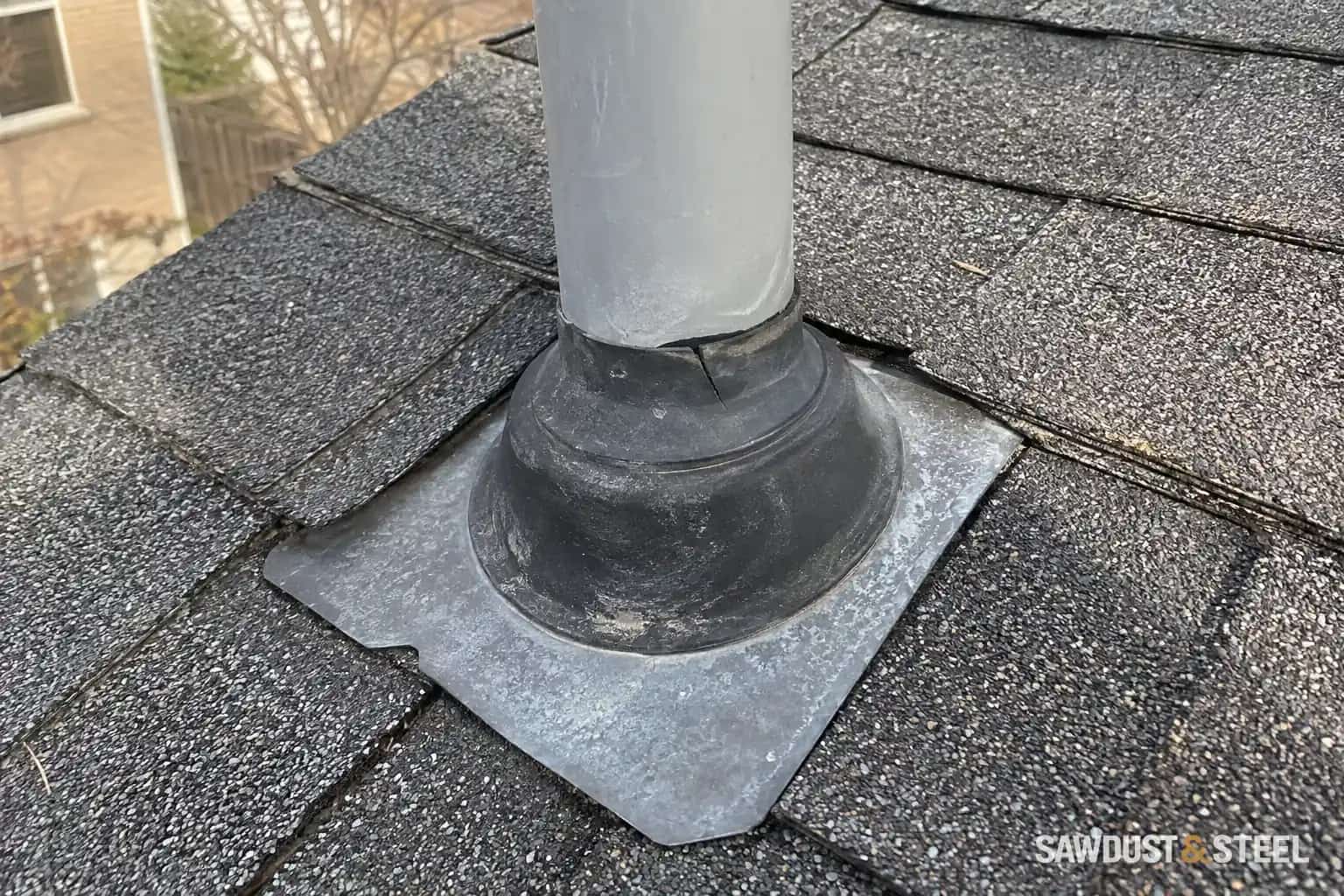 Cracked rubber collar around a plumbing vent pipe on an asphalt-shingle roof.
