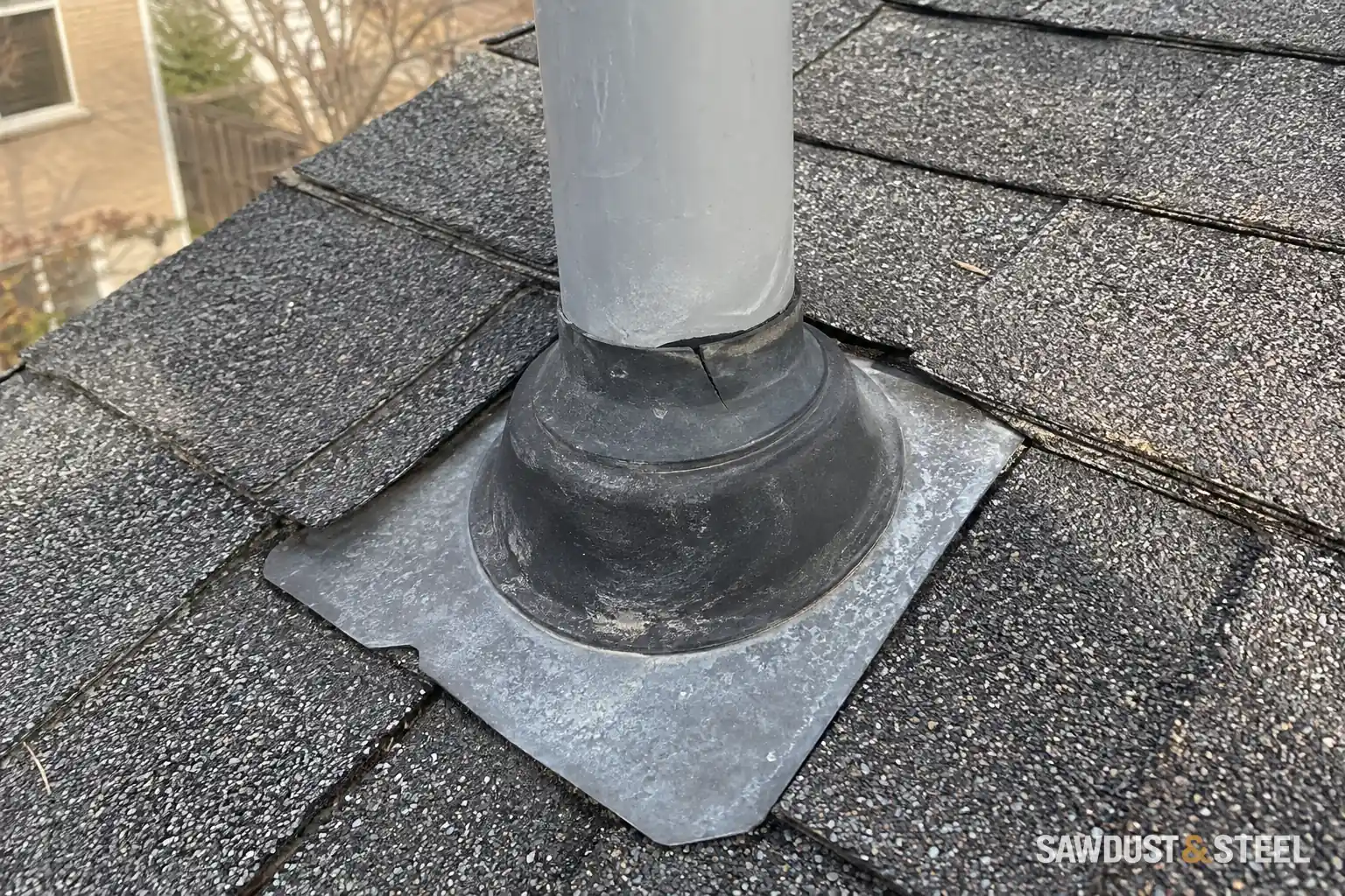 Cracked rubber collar around a plumbing vent pipe on an asphalt-shingle roof.