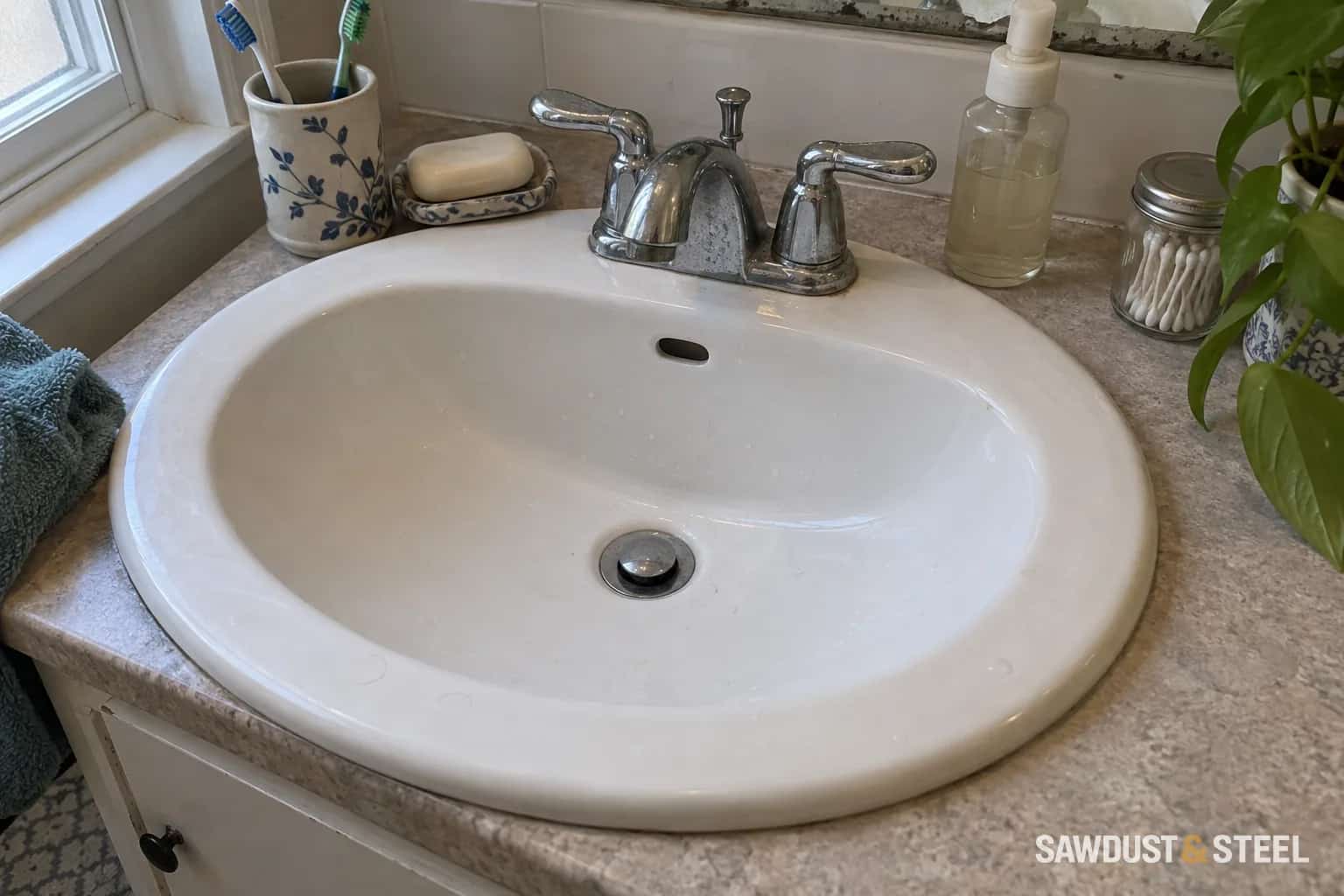 Overflow opening and chrome drain in a white bathroom basin.