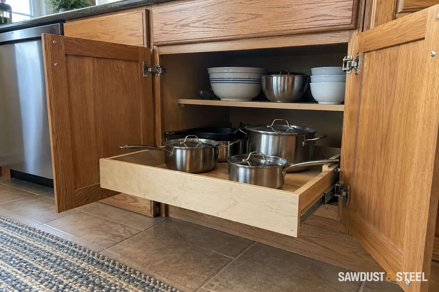 Wooden pull-out tray holding pots extended beyond two open cabinet doors