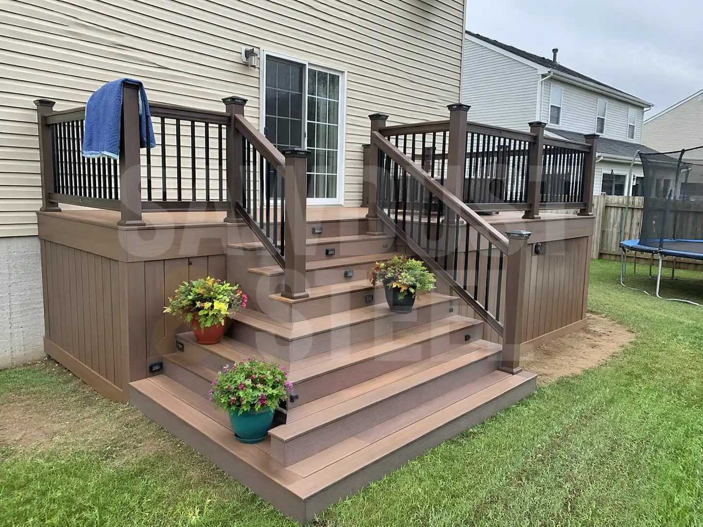 Composite deck with dark aluminum railing and stairs leading to a stone patio