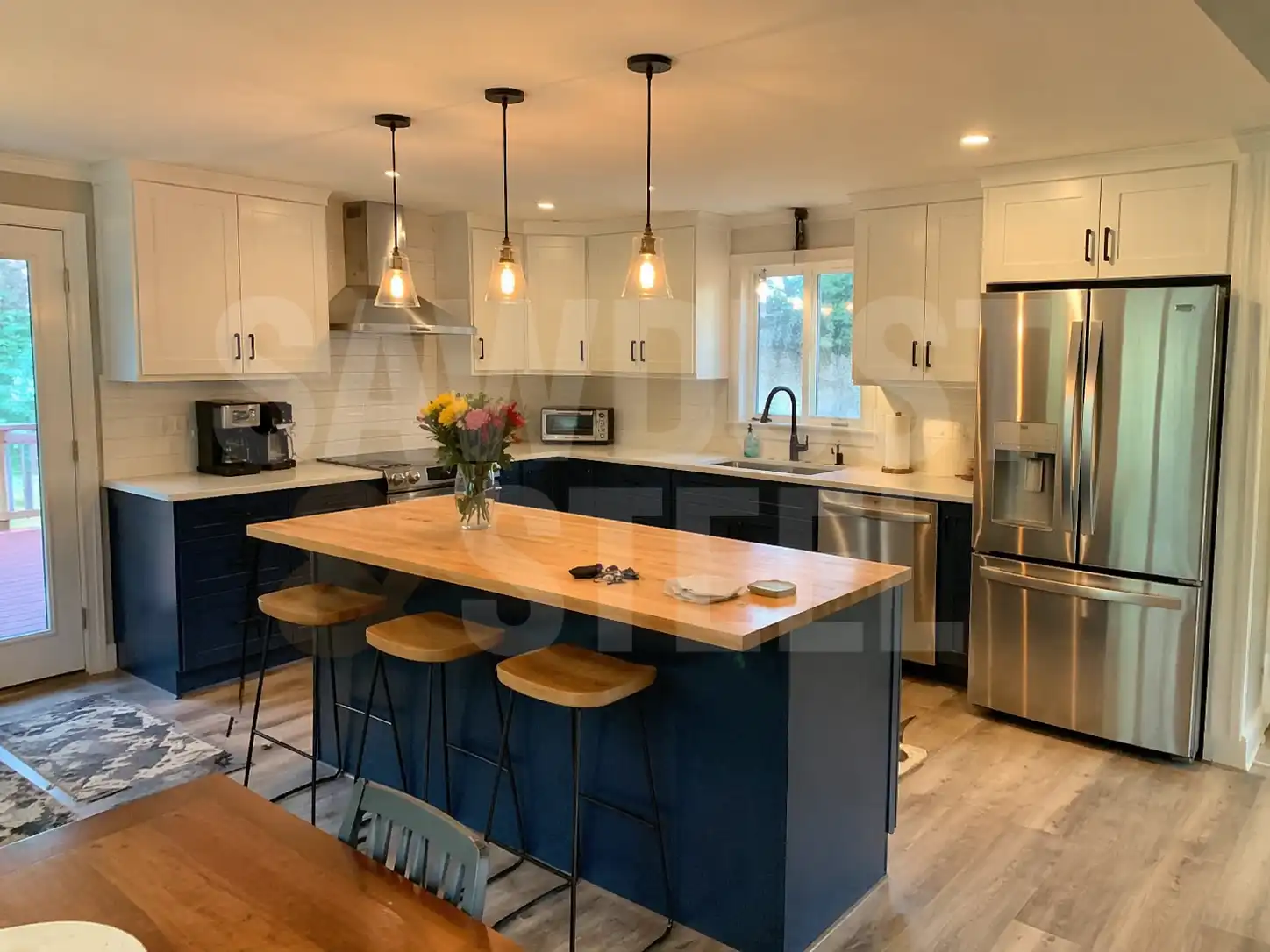 Kitchen with a blue island, butcher-block top, and pendant lighting