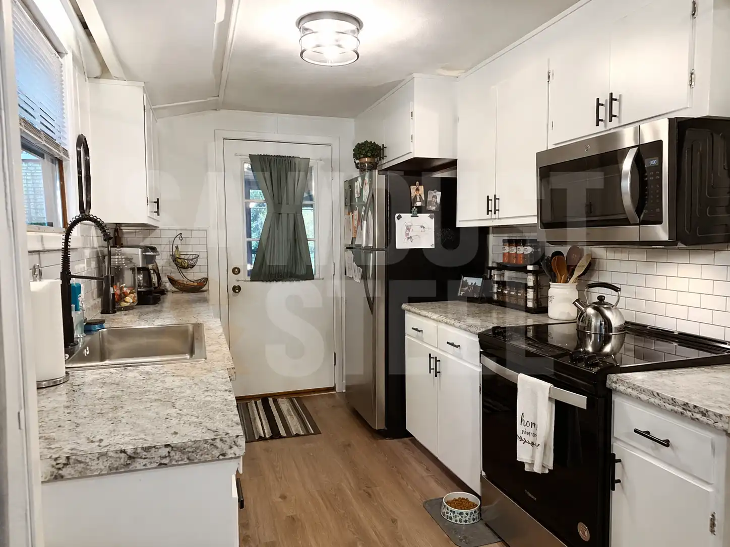 Compact galley kitchen with shaker cabinets and granite counters