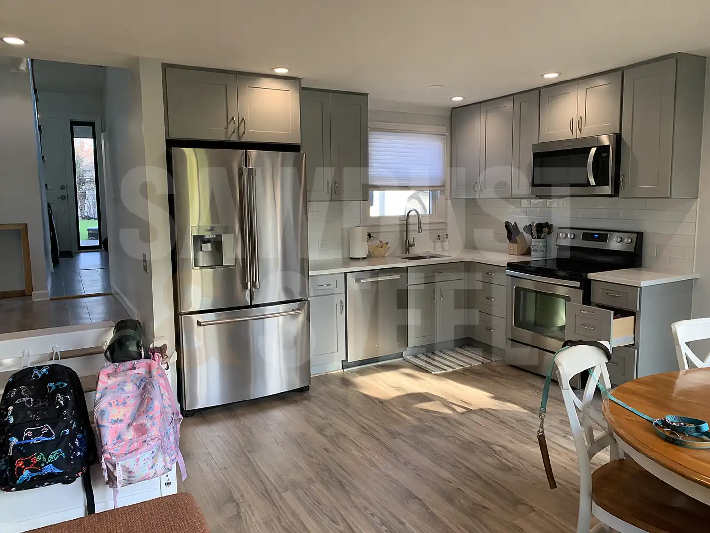 Grey kitchen cabinets with stainless appliances in an open layout