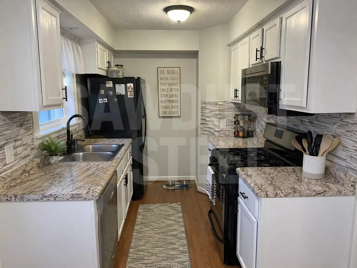 White galley kitchen with stone backsplash and granite counters