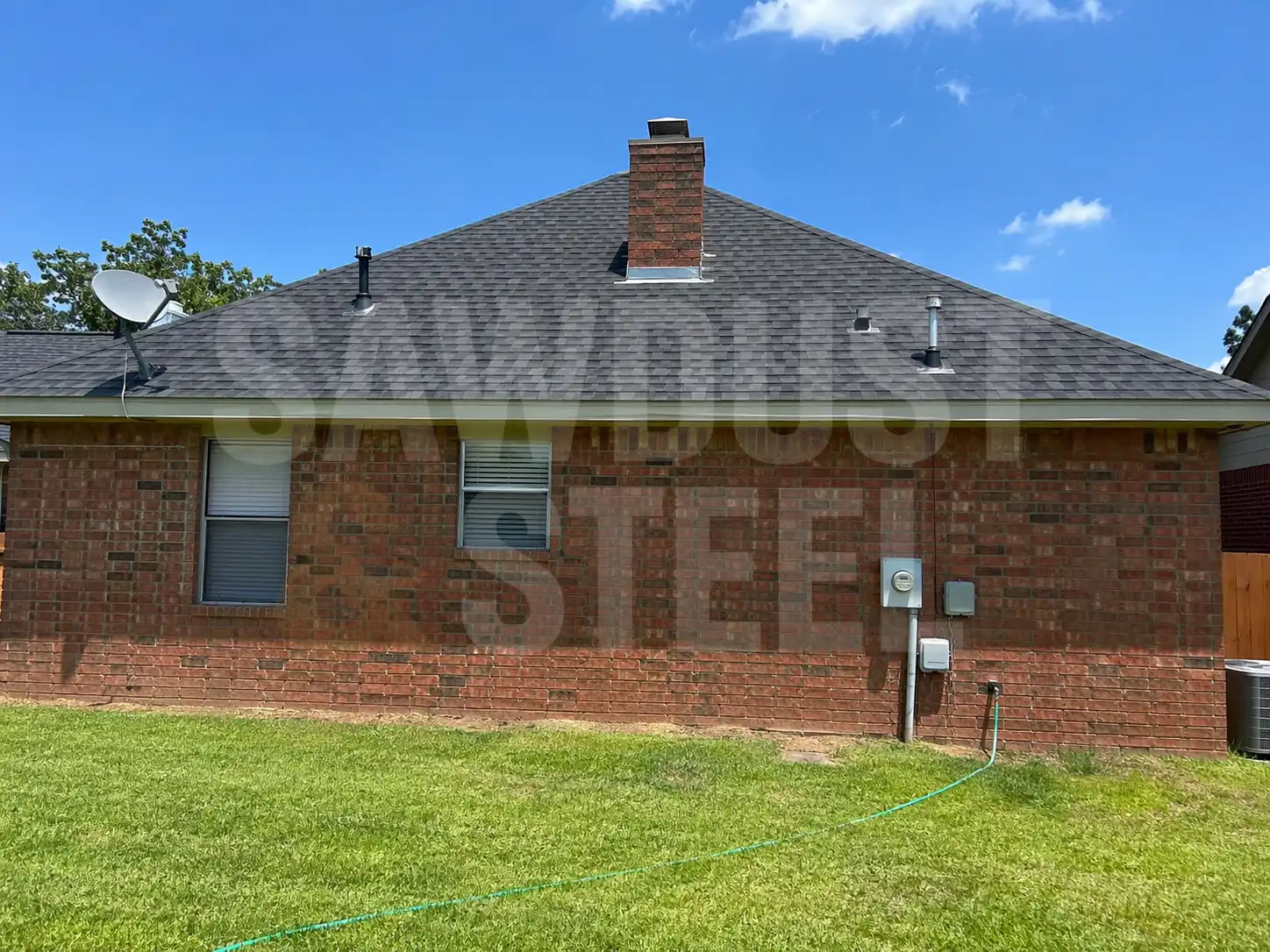 Aerial-style view of a brick house with shingle roof and chimney