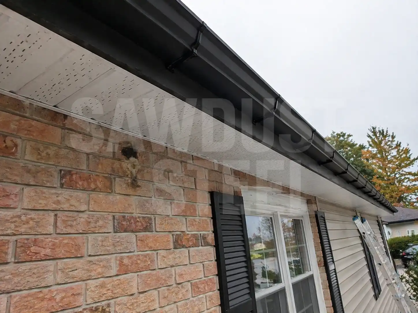 Dark gutters, soffit, and fascia along a brick wall — the eave detail where ice dams start