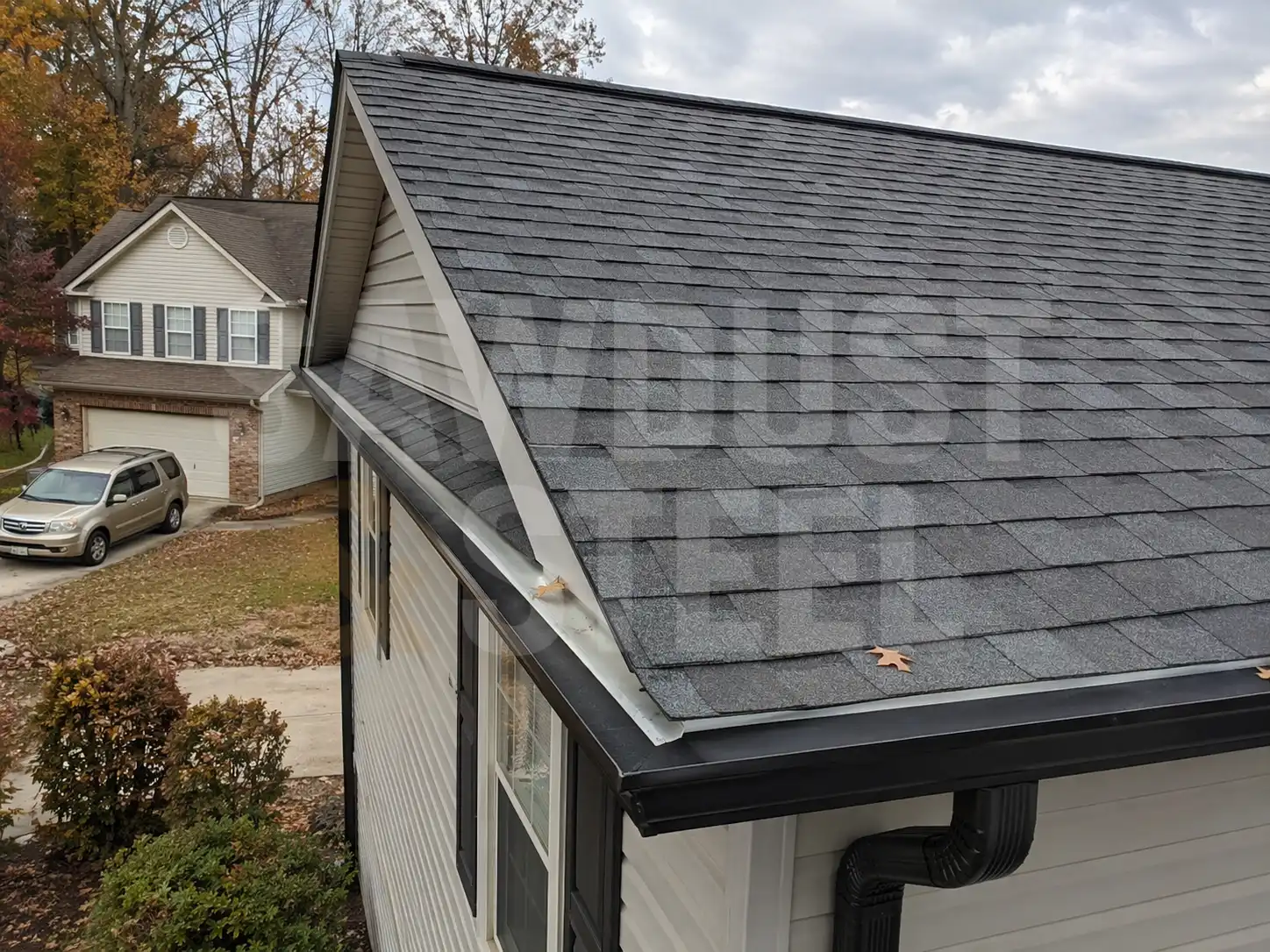 Gray architectural shingles on a gable roof with new gutters and downspouts