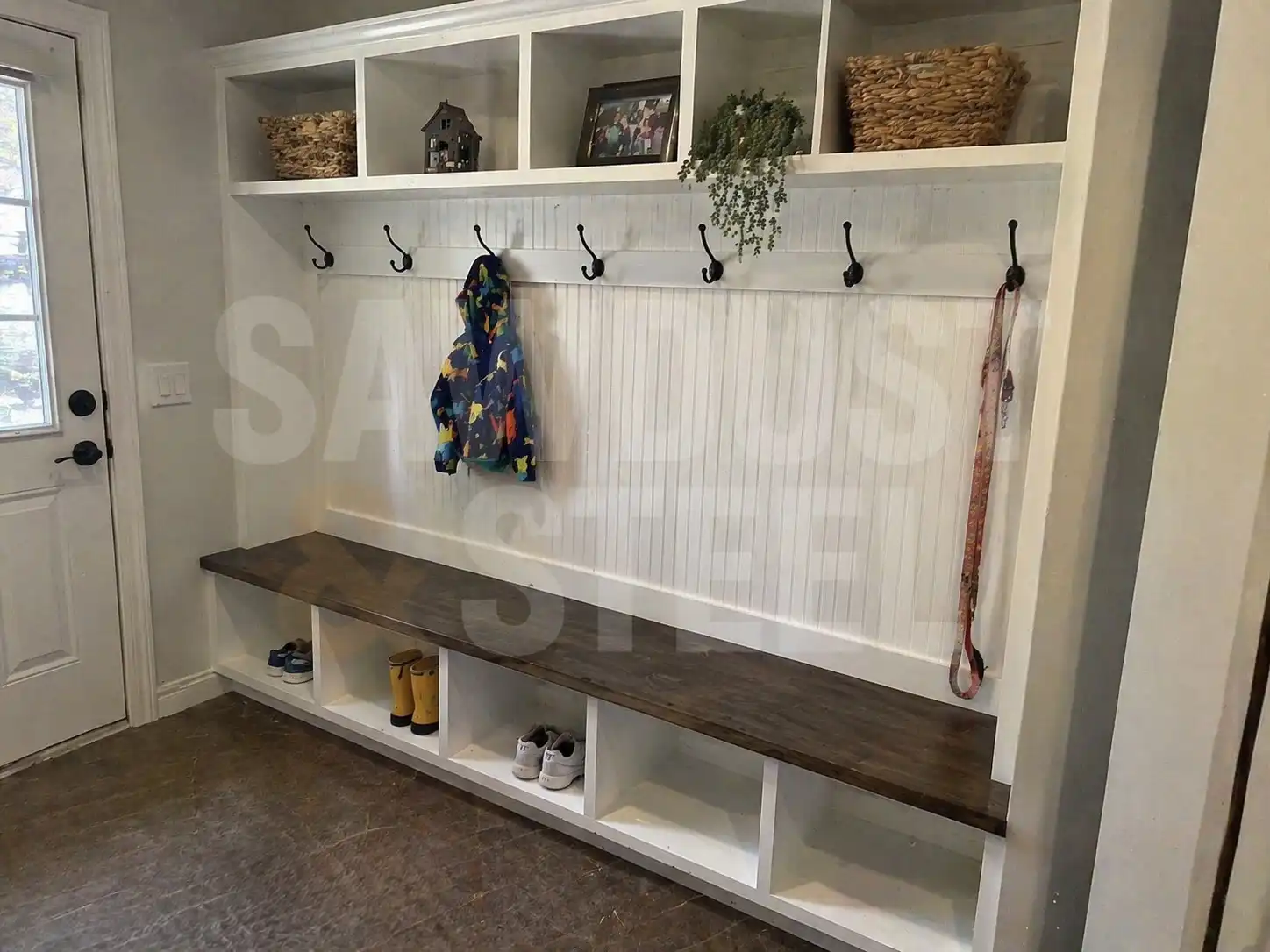 Mudroom bench with black coat hooks, upper baskets and open shoe compartments